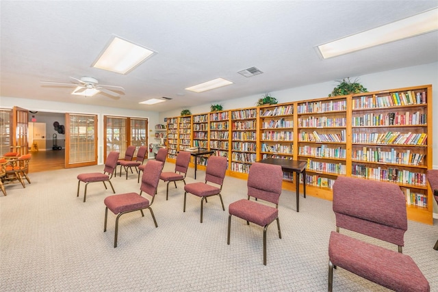 sitting room with carpet flooring, bookshelves, and visible vents