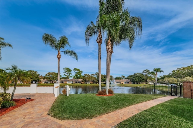 view of home's community featuring fence, a water view, and a lawn