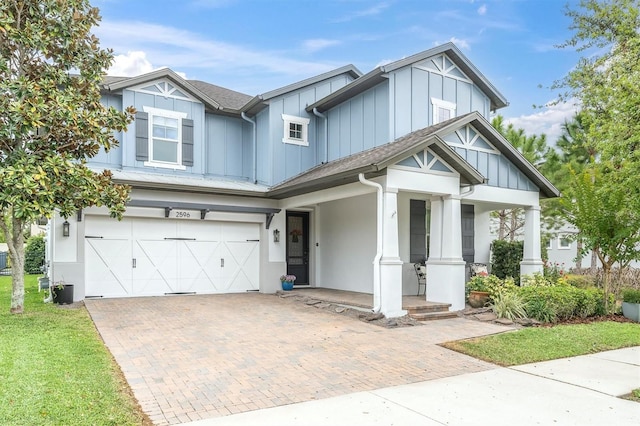 view of front of house featuring board and batten siding, a porch, decorative driveway, and a garage