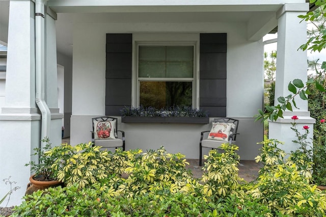 property entrance with covered porch and stucco siding