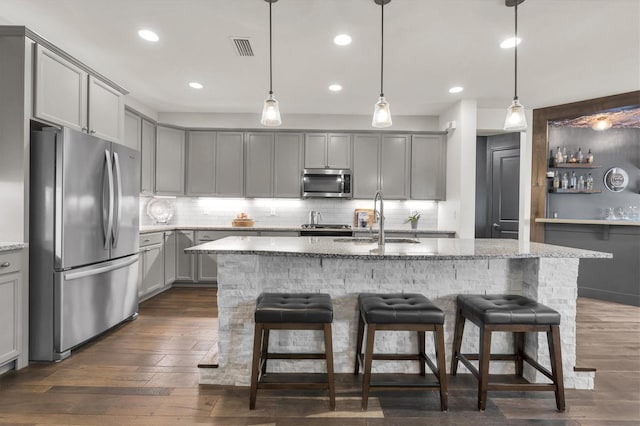 kitchen featuring visible vents, stainless steel appliances, a sink, dark wood-style floors, and gray cabinets