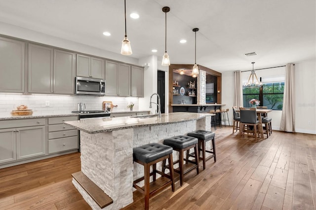 kitchen featuring gray cabinetry, tasteful backsplash, a sink, and stainless steel appliances