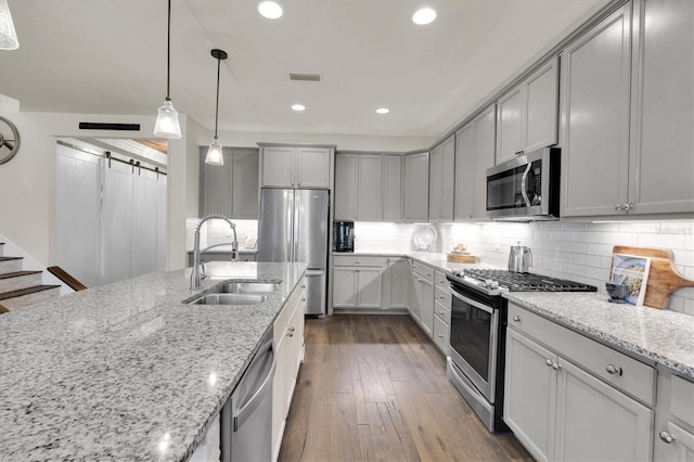 kitchen featuring dark wood-style flooring, stainless steel appliances, decorative backsplash, a sink, and visible vents
