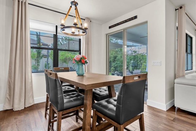 dining space with baseboards, a notable chandelier, and wood-type flooring