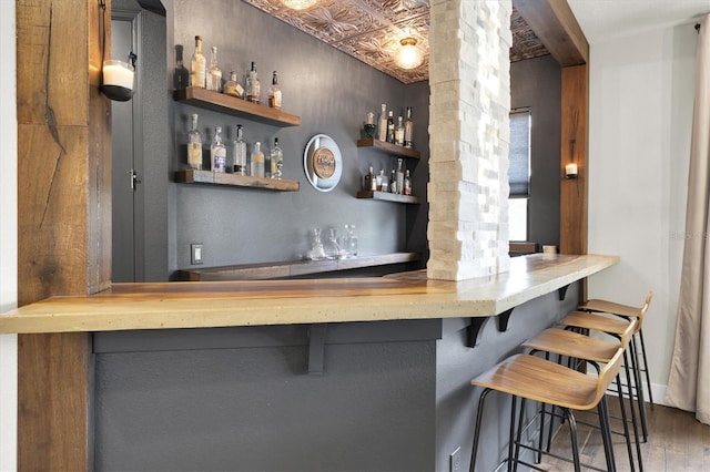 bar with a bar, wood finished floors, and an ornate ceiling