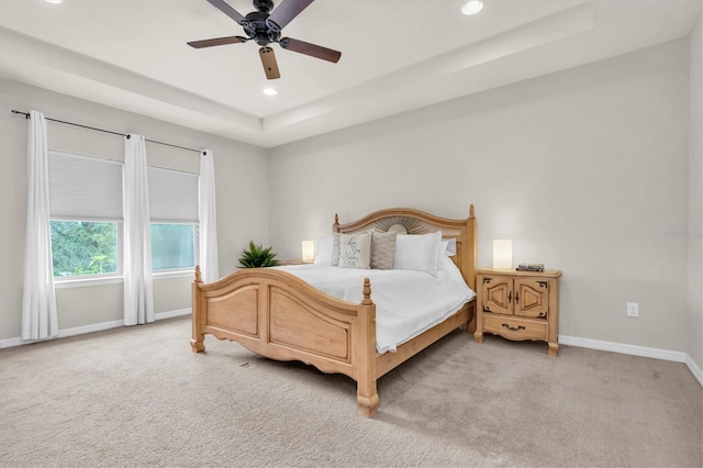 bedroom featuring a ceiling fan, light carpet, a raised ceiling, baseboards, and recessed lighting