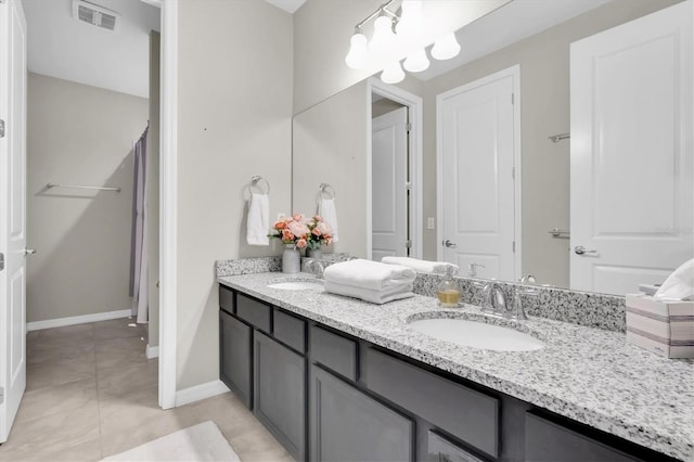bathroom with double vanity, visible vents, baseboards, and a sink