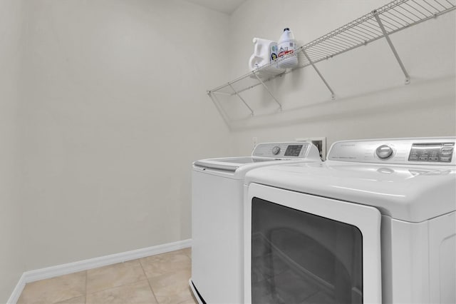clothes washing area with light tile patterned flooring, baseboards, separate washer and dryer, and laundry area