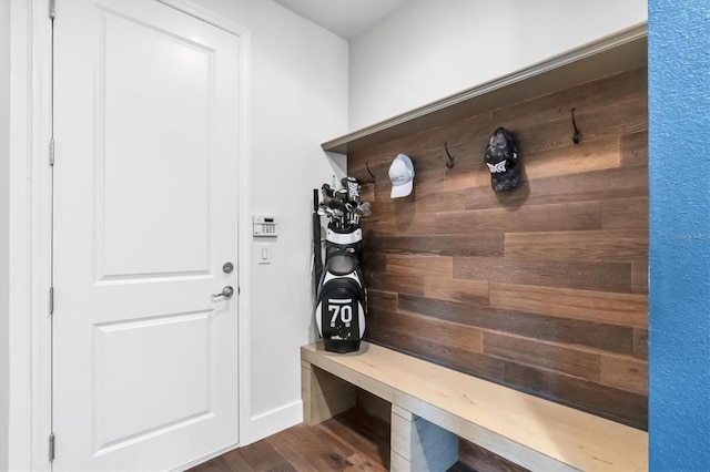 mudroom featuring dark wood-type flooring and wood walls