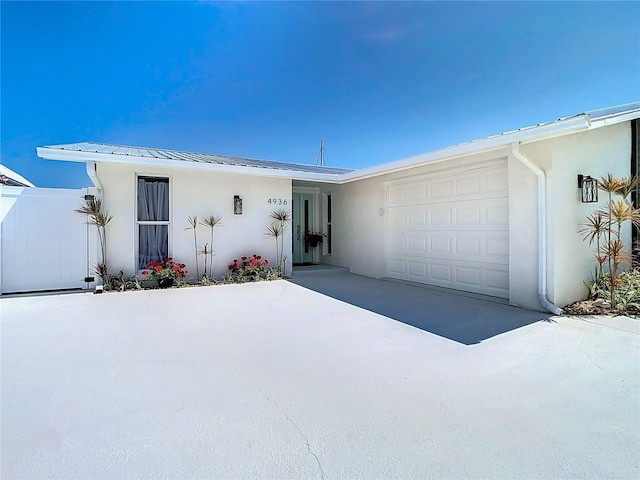 4936 Dory Dr, New Port Richey, FL 34652 - view of front of property featuring stucco siding, metal roof, a garage, and fence
