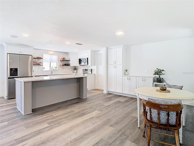 4936 Dory Dr, New Port Richey, FL 34652 - kitchen with decorative backsplash, visible vents, stainless steel appliances, open shelves, and a center island