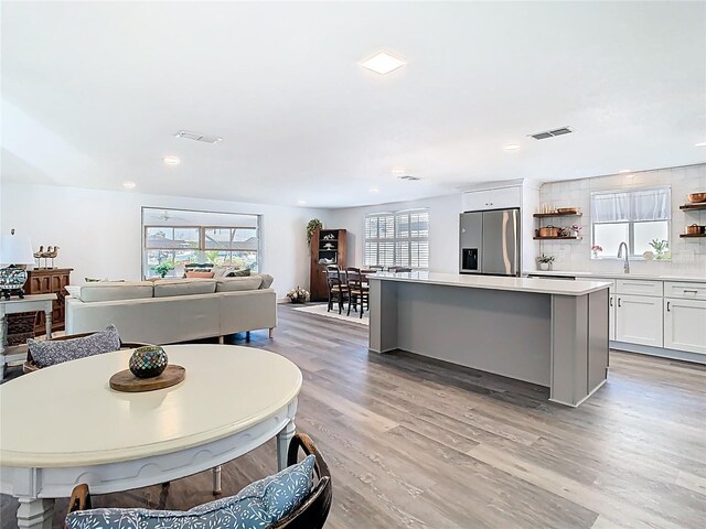 4936 Dory Dr, New Port Richey, FL 34652 - kitchen with stainless steel fridge, open shelves, a kitchen island, a sink, and visible vents