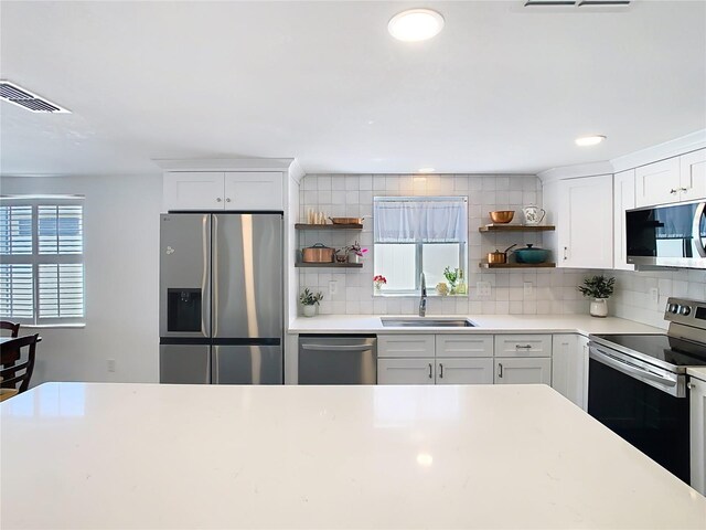 4936 Dory Dr, New Port Richey, FL 34652 - kitchen with open shelves, backsplash, a sink, white cabinets, and appliances with stainless steel finishes