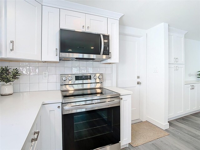 4936 Dory Dr, New Port Richey, FL 34652 - kitchen with light countertops, white cabinetry, tasteful backsplash, light wood-type flooring, and stainless steel appliances