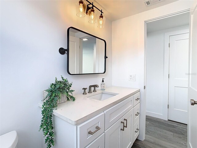 4936 Dory Dr, New Port Richey, FL 34652 - half bathroom featuring toilet, visible vents, wood finished floors, and vanity