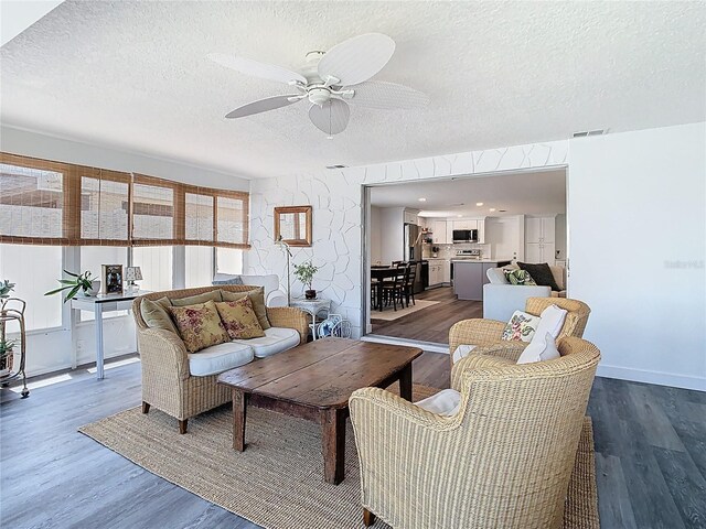 4936 Dory Dr, New Port Richey, FL 34652 - living room featuring a textured ceiling, visible vents, baseboards, ceiling fan, and wood finished floors