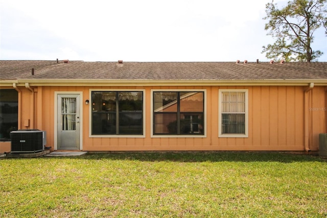 9321 Whitstone Ct, New Port Richey, FL 34655 - back of property with a lawn, a shingled roof, central air condition unit, and board and batten siding