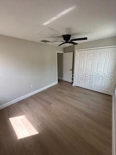 unfurnished bedroom featuring baseboards, wood finished floors, and ceiling fan