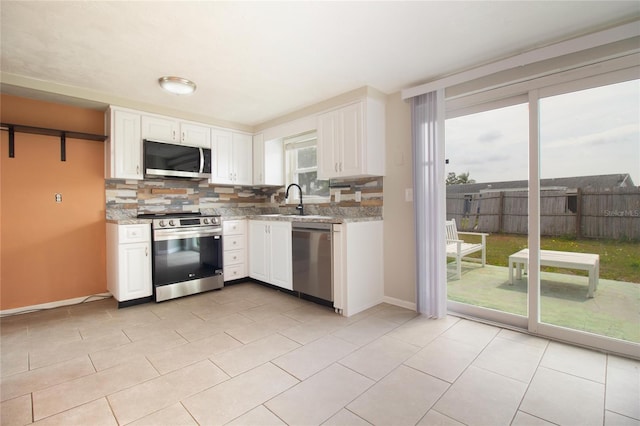 2620 Baltic Pl, Holiday, FL 34691 - kitchen featuring white cabinets, stainless steel appliances, a sink, and backsplash