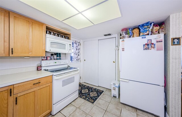 4107 Glissade Dr, New Port Richey, FL 34652 - kitchen with light tile patterned flooring, light countertops, light brown cabinets, white appliances, and visible vents