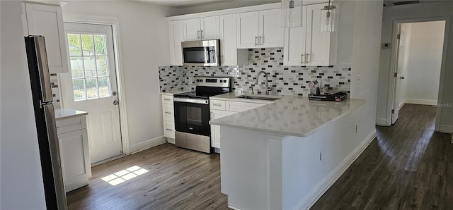807 S Castle Ct, Tampa, FL 33612 - kitchen featuring dark wood-style flooring, a peninsula, stainless steel appliances, white cabinetry, and a sink