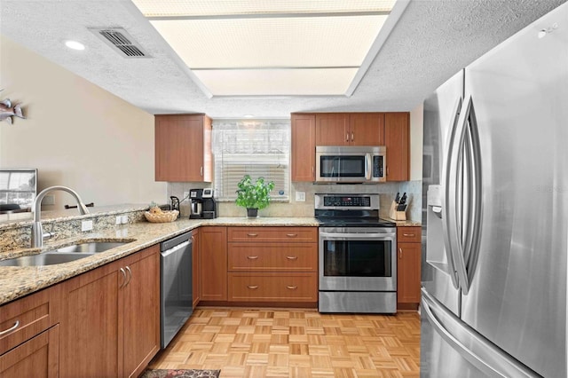 4058 Centavo Ct, Hernando Beach, FL 34607 - kitchen with appliances with stainless steel finishes, a sink, brown cabinets, light stone countertops, and a textured ceiling