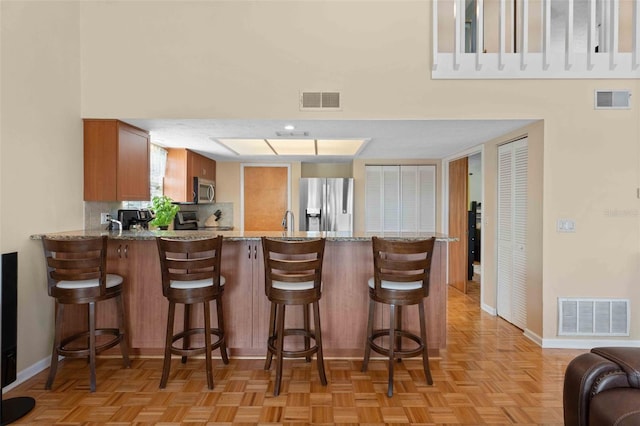 4058 Centavo Ct, Hernando Beach, FL 34607 - kitchen with stainless steel appliances, a peninsula, baseboards, light stone countertops, and a high ceiling