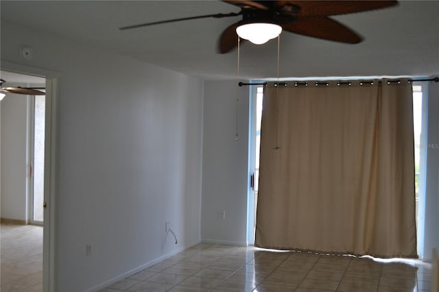 spare room with ceiling fan, light tile patterned floors, and baseboards