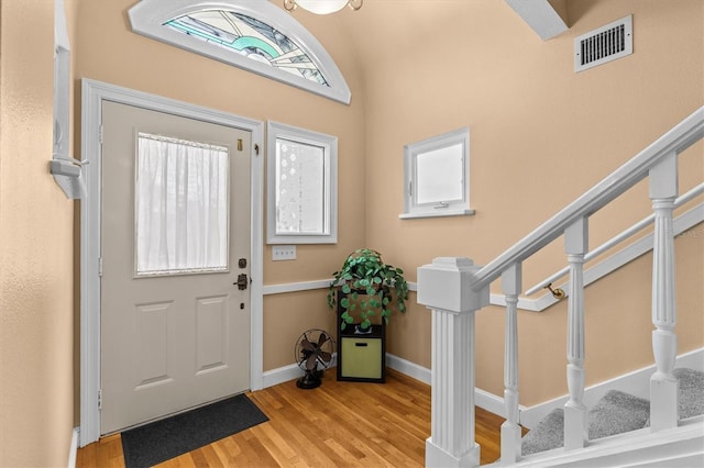 foyer entrance with wood finished floors, stairs, and visible vents