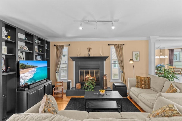 living area with a tile fireplace, a wealth of natural light, ornamental molding, and wood finished floors