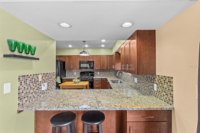 kitchen featuring backsplash, black appliances, light stone countertops, and a sink