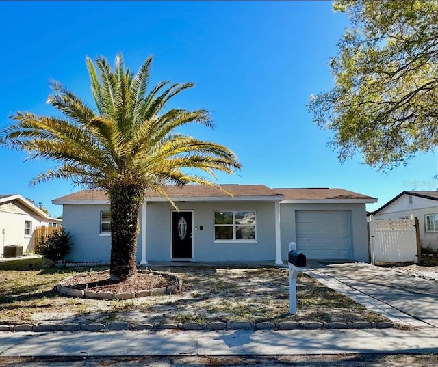 ranch-style house with concrete driveway, stucco siding, fence, and a garage