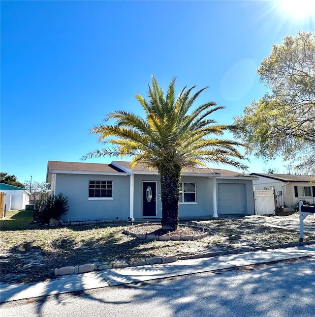 ranch-style house featuring fence, a garage, and stucco siding