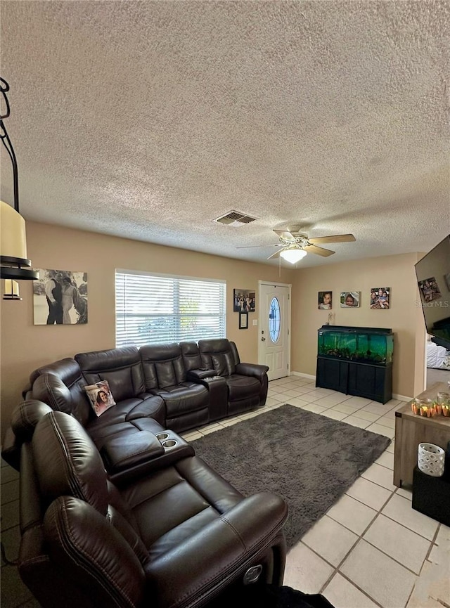 living area with light tile patterned floors, a textured ceiling, visible vents, and a ceiling fan