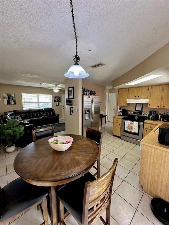 dining space with a textured ceiling, light tile patterned flooring, and ceiling fan