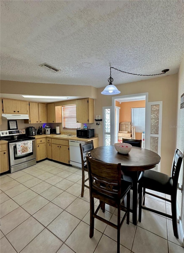 dining area with light tile patterned flooring, a textured ceiling, and visible vents