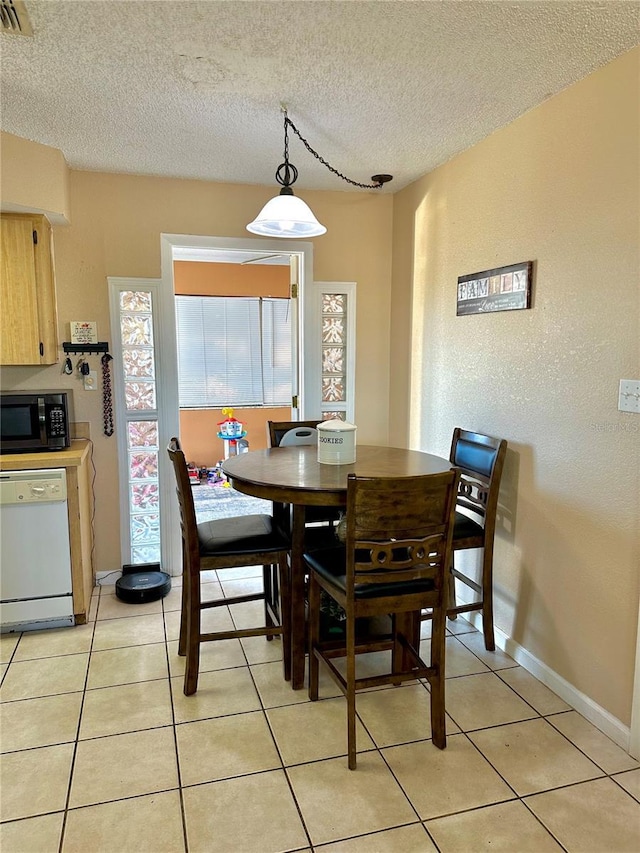 dining area with a textured ceiling, visible vents, baseboards, and light tile patterned floors