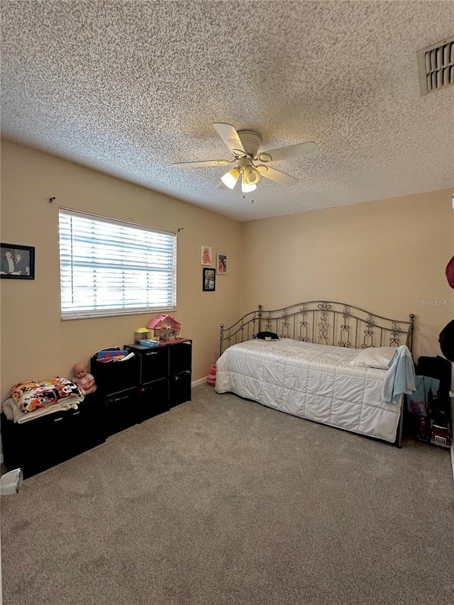 carpeted bedroom featuring a textured ceiling, visible vents, and a ceiling fan