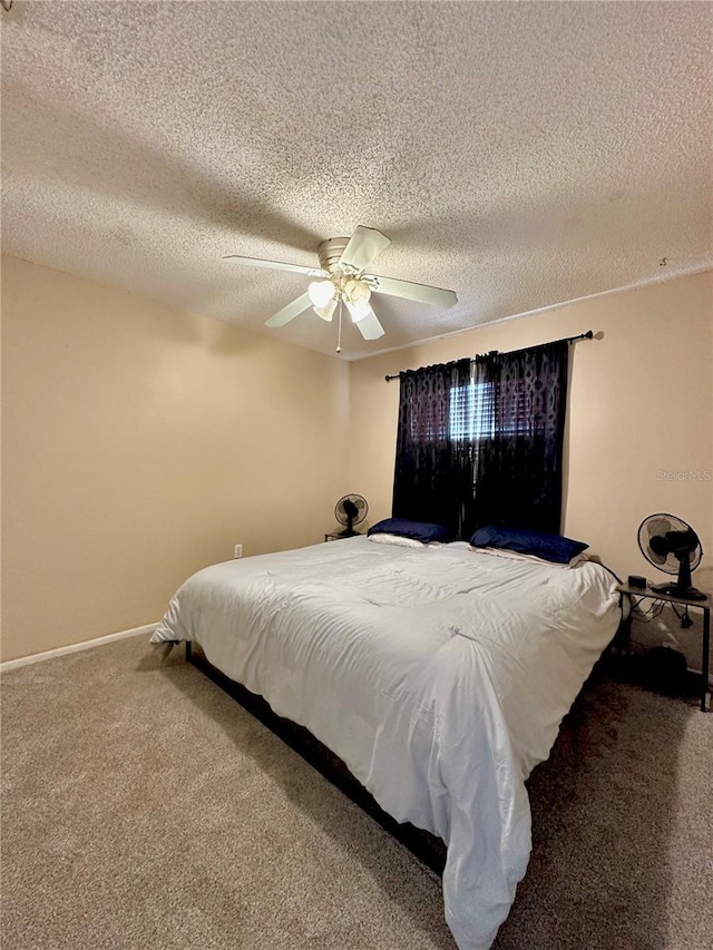bedroom with carpet, a textured ceiling, baseboards, and a ceiling fan