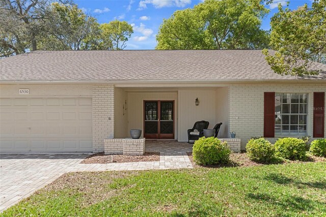 6530 Pine Meadows Dr, Spring Hill, FL 34606 - ranch-style house featuring driveway, roof with shingles, brick siding, a front lawn, and a garage