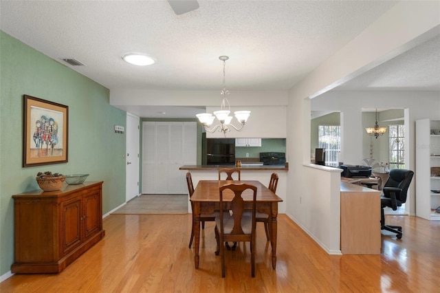 6530 Pine Meadows Dr, Spring Hill, FL 34606 - dining space with a textured ceiling, light wood-style floors, and a notable chandelier