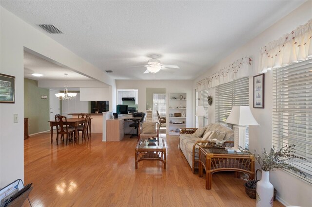 6530 Pine Meadows Dr, Spring Hill, FL 34606 - living room featuring ceiling fan with notable chandelier, light wood-style floors, a textured ceiling, and visible vents