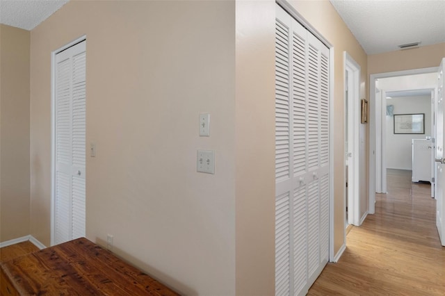 6530 Pine Meadows Dr, Spring Hill, FL 34606 - corridor featuring baseboards, light wood-type flooring, visible vents, and a textured ceiling