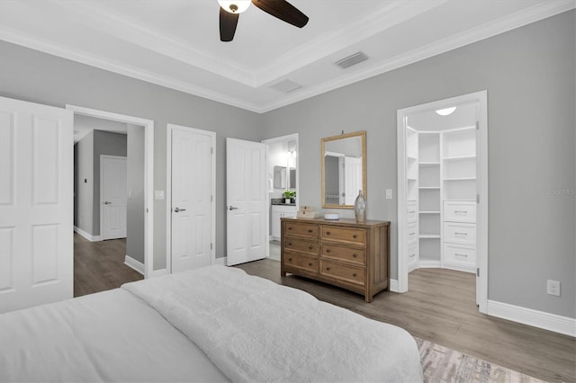 3465 Bumelia Ln, New Port Richey, FL 34655 - bedroom featuring a walk in closet, crown molding, baseboards, visible vents, and wood finished floors
