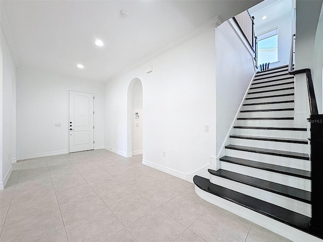 stairway featuring arched walkways, baseboards, recessed lighting, and tile patterned flooring