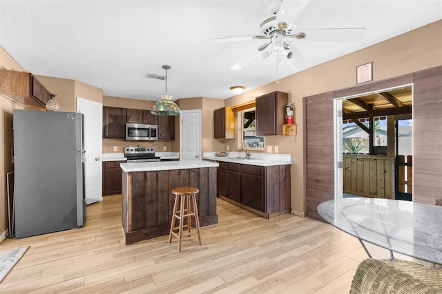 kitchen with light countertops, a center island, a sink, visible vents, and appliances with stainless steel finishes