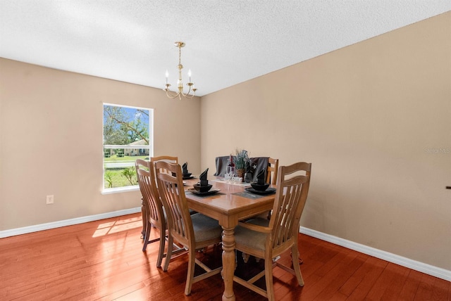 dining area with hardwood / wood-style floors, baseboards, a chandelier, and a textured ceiling