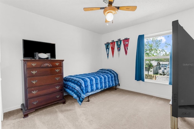 bedroom featuring light carpet, baseboards, and ceiling fan