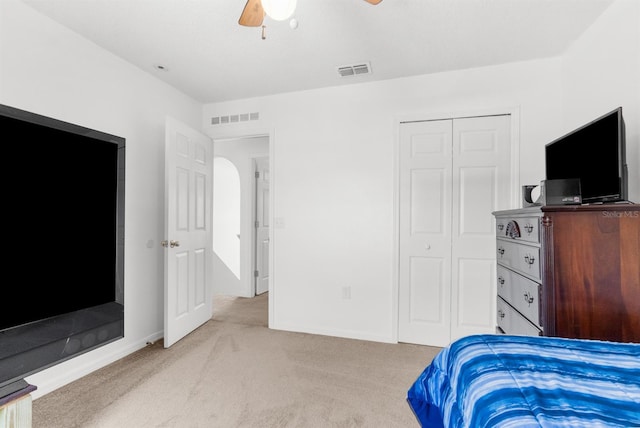 bedroom with light carpet, visible vents, a closet, and a ceiling fan