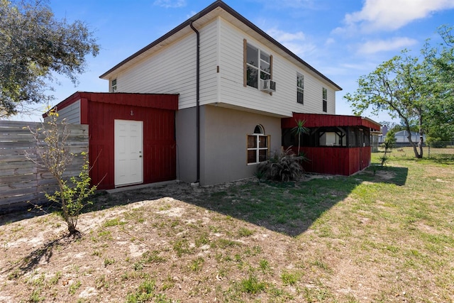 back of property featuring a lawn, cooling unit, an outbuilding, and fence